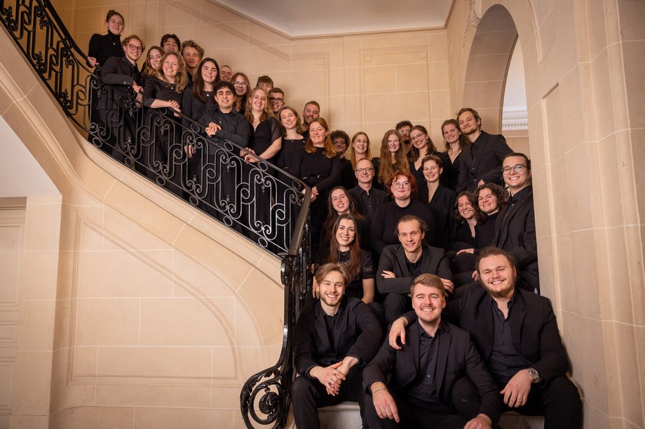 Kammerchor der HfMT viele schwarz gekleidete Menschen lachend auf geschwungener Innentreppe