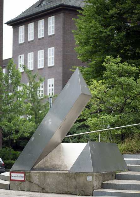 geometrische Metallskulptur vor einem Backsteingebäude