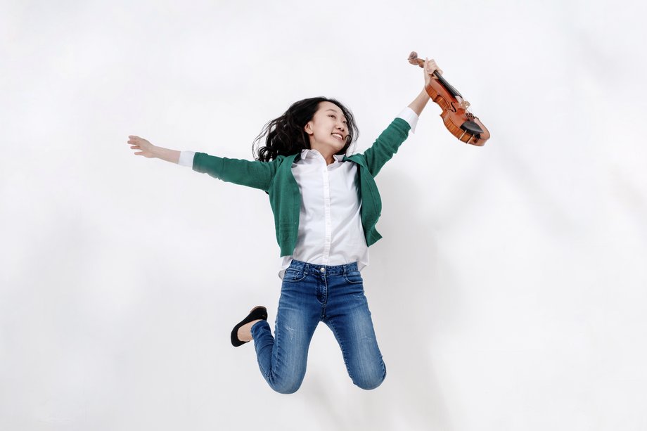 Foto von einer springenden Frau mit Violine in der Hand