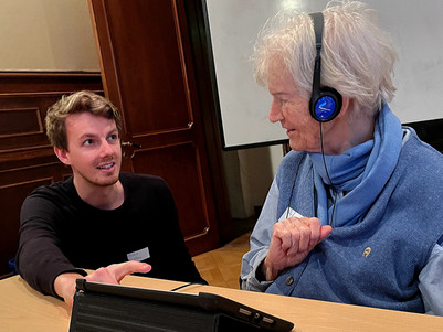 Ein junger Mann zeigt einer älteren Frau etwas auf einem Tablet