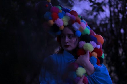 Person mit bunter Perücke aus Kugeln in der Dämmerung