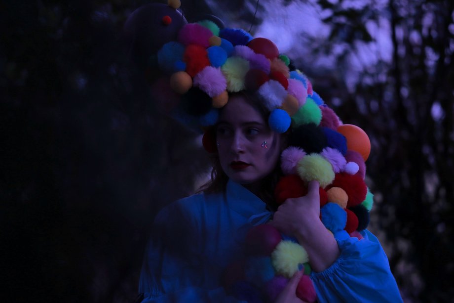 Person mit bunter Perücke aus Kugeln in der Dämmerung
