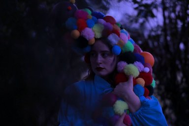 Person mit bunter Perücke aus Kugeln in der Dämmerung