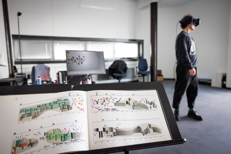 Computermusik_Foto Notenständer im Vordergrund und Person mit 3D-Bille im Hintergrund