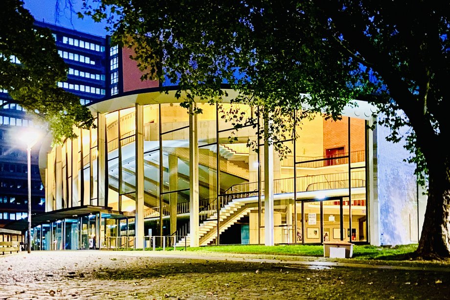 Audimax Ansicht eines Gebäudes mit Glasfassade am Abend im Schein einer Straßenlaterne