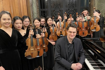 zwölf Violinist:innen und ein Pianist mit ihren Instrumenten