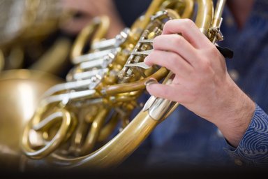 Detailaufnahme Hand auf Ventilen eines Horn-Instruments