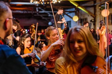 2025-12-11 Stegreif Orchester Photo of many people playing instruments at a festive location