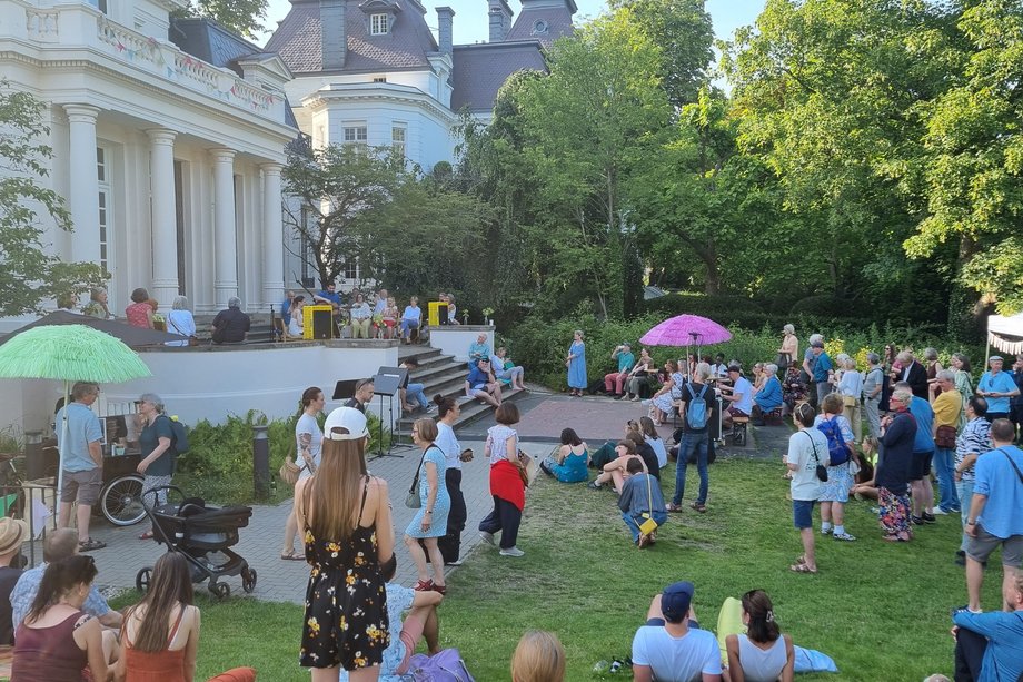 HfMT Sommerfest 2025 viele Menschen im geschmückten Garten der Hochschule mit Konzert und Gesprächen