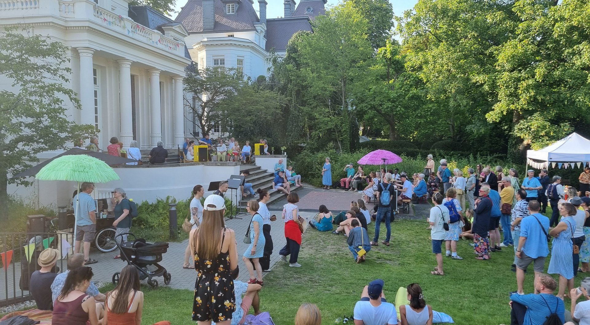 HfMT Sommerfest 2025 viele Menschen im geschmückten Garten der Hochschule mit Konzert und Gesprächen