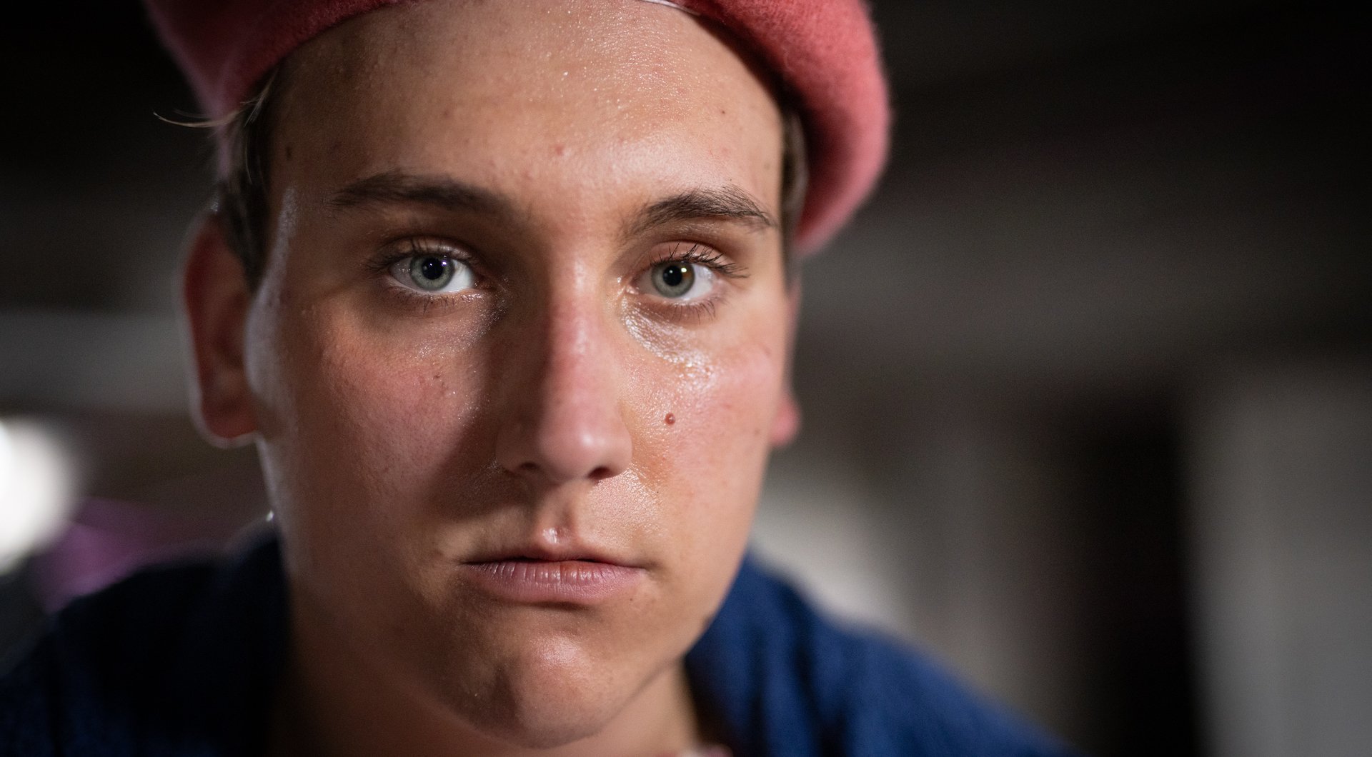 made-up actor with green eyes and red cap in close-up