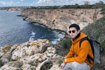 Yanting Hou vor einem Bergpanorama hockend