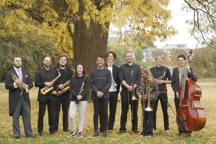 Ensemble von 10 Personen mit Instrumenten auf einer Wiese