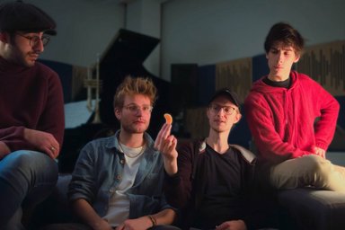 2026-04-10 Jazz Meets School Vier Personen schauen ein Mandarinenstück an.