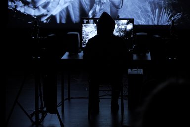 Person from behind in front of a large screen in a dark event room