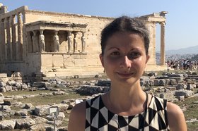 Portrait of a dark-haired woman in front of an ancient building in the background