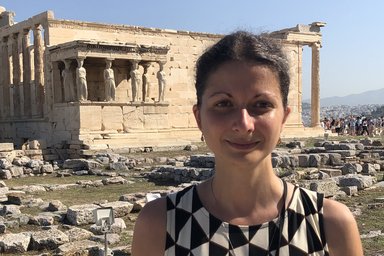 Portrait of a dark-haired woman in front of an ancient building in the background