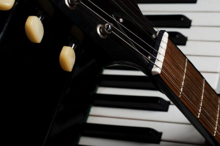 Keys & Guitars Recital Night Nahaufnahme von einer Gitarre, die an einem Klavier lehnt