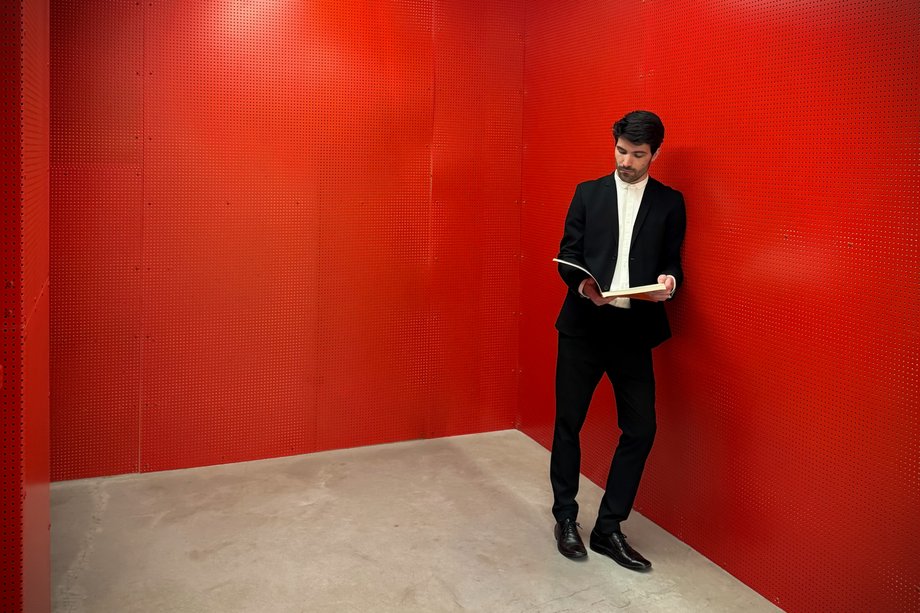Image of a man leaning against a red wall