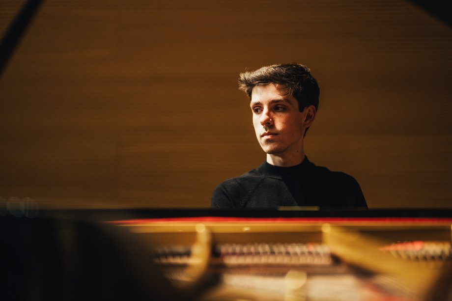 Portrait eines Mannes, der am Klavier sitzt und zur Seite schaut