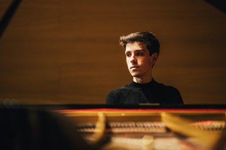 Portrait eines Mannes, der am Klavier sitzt und zur Seite schaut