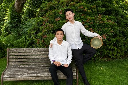 Yanting Hou zwei Schlagzeuger: einer sitzend auf der Bank, einer stehend daneben