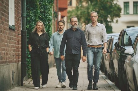 vier Personen laufen auf einem Gehweg der Kamera entgegen