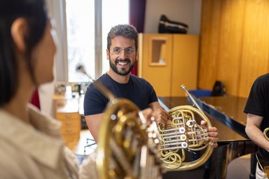 Unterricht.AdriánDíazMartínez 1 3 Personen mit Horn in der Hand in Kommunikation miteinander