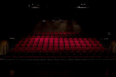 Blick auf rote, leere Theatersessel in einem Theatersaal