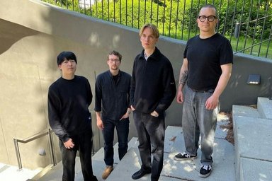 four people dressed in black and gray on a staircase