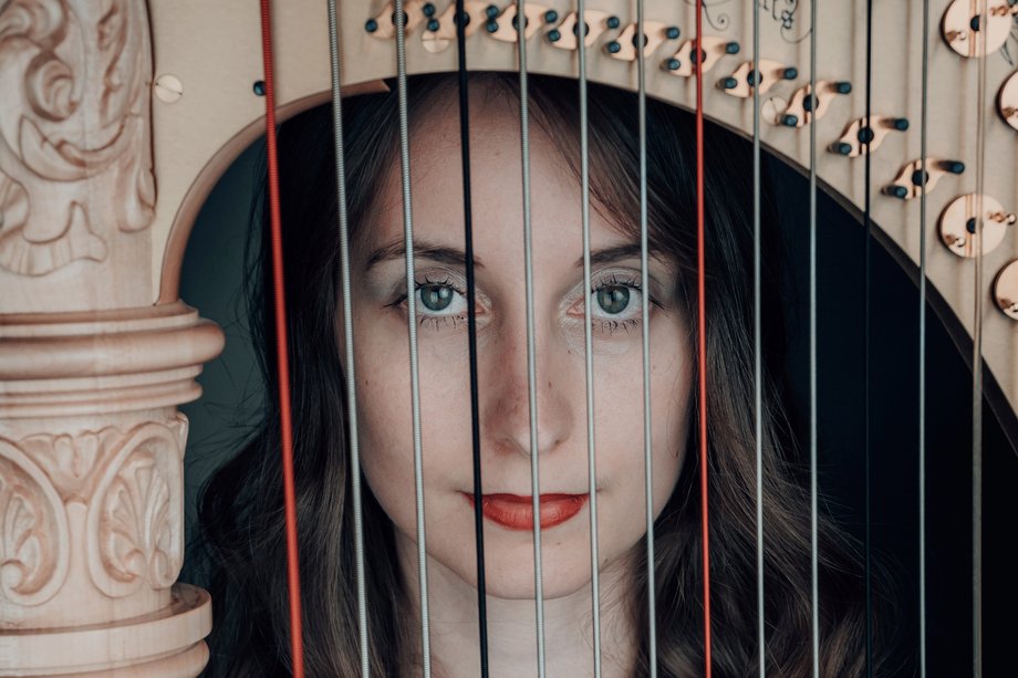 Chiara Sax blickt durch die Saiten ihrer Harfe in die Kamera