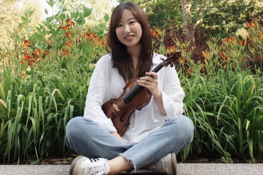 Eunsong Jung mit Violine vor einem Blumenbeet