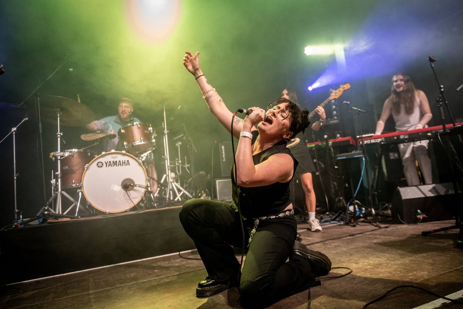 2025-08-21 Popkurs 2025 Foto von einer Frau mit Band, die auf einer Bühne singt.