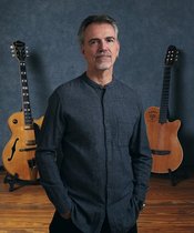 Portrait of Roland Cabezas with two guitars in the background