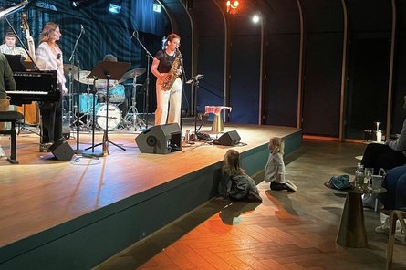 Künstlerin auf der Bühne, zwei Kinder direkt vor der Bühne sitzend