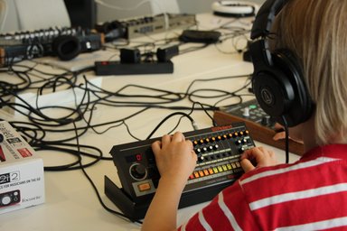 Synthesizer Workshop für Kinder Kind von hinten, was an einem Mischpult sitzt