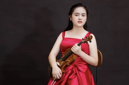 Li Yuan in einem roten Kleid mit Viola im Arm