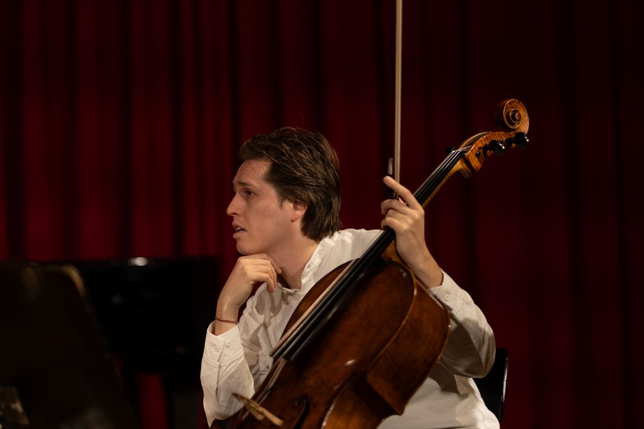 Person mit Cello in nachdenklicher Pose, Seitenansicht