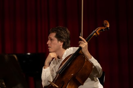 Person mit Cello in nachdenklicher Pose, Seitenansicht
