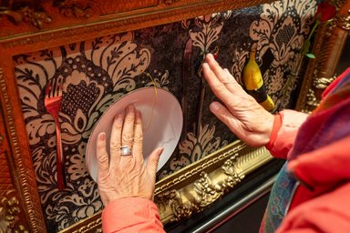 Hands are touching a plate and cutlery that have been stuck to a wall