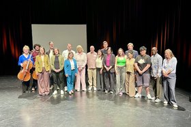 Besuch der Senatorin zu Projektstart Viele Menschen stehen für ein Gruppenfoto auf einer Theaterbühne