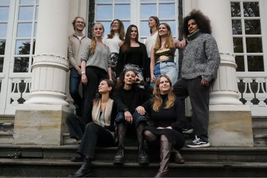 2025-12-15 cozy, cool and cheery 10 Personen auf einer Treppe, alle schauen in unterschiedliche Richtungen