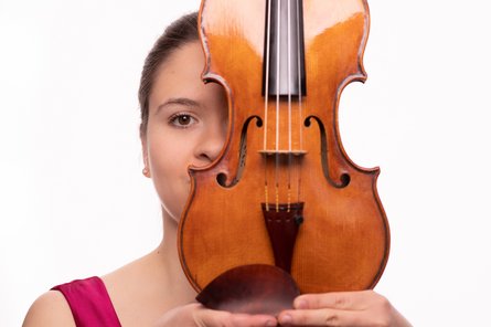 Aila Katalin Krohn im Porträt, ihr Gesicht ist halb von der Violine verdeckt