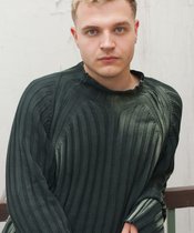 Blonde Peron mit grünem Pullover.