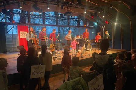 Musiker:innen und Kinder auf der Bühne der JazzHall beim Überreichen der Blumen