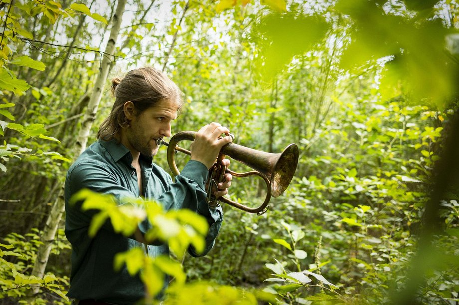 Person mit Trompete im Wald