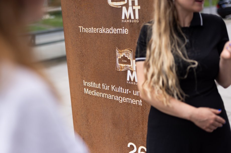 KMM Promotion Eine Studierende neben dem Eingangsportal zum KMM