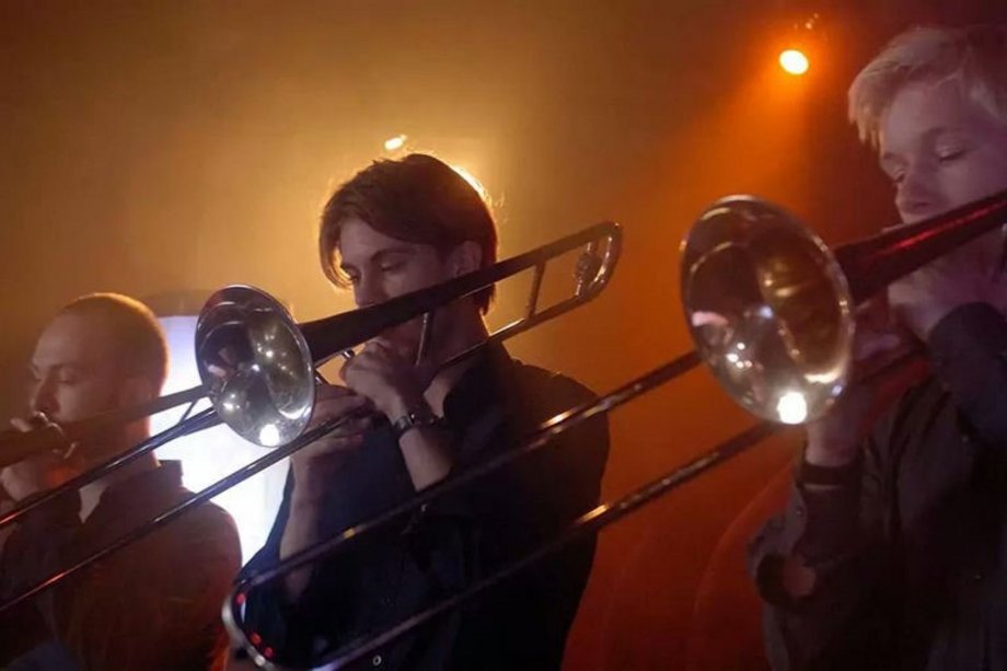 Personen mit Blechblasinstrumenten in orangem Licht