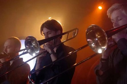 Personen mit Blechblasinstrumenten in orangem Licht
