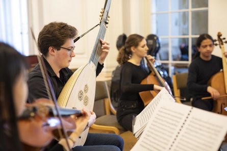 vier Personen mit barocken Saiteninstrumenten und Notenständern